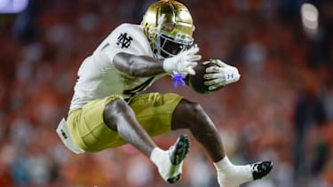Notre Dame Fighting Irish Running Back Jeremiyah Love (#4) springt über Miami Hurricanes Defensive Back Dylan Day (#23) im vierten Viertel im Hard Rock Stadium in Miami, Florida