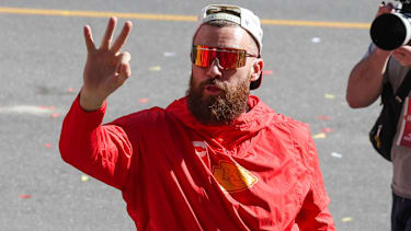 Travis Kelce trägt einen Wrestling-Championgürtel und zeigt drei Finger, um drei Titel zu symbolisieren, während der Super-Bowl-LVIII-Siegerparade der Kansas City Chiefs am 14. Februar 2024 in Kansas City, Missouri.