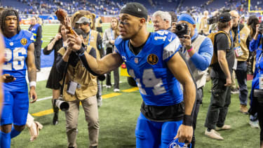 Nov 28, 2024; Detroit, Michigan, USA; Detroit Lions wide receiver Amon-Ra St. Brown (14) tosses a turkey leg to a fan after the annual Thanksgiving Day game defeating the Chicago Bears at Ford Field. Mandatory Credit: David Reginek-Imagn Images 