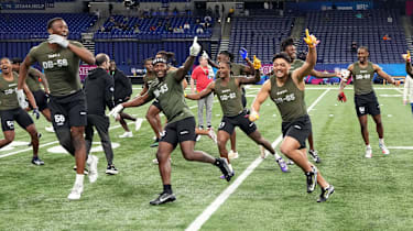 Minnesota-Defensive Back Tyler Nubin (DB56), Georgia-Defensive Back Tykee Smith (DB63) und Utah-Defensive Back Sione Vaki (DB65) reagieren gemeinsam mit anderen Athleten während der Übungen beim NFL Combine 2024 im Lucas Oil Stadium.
