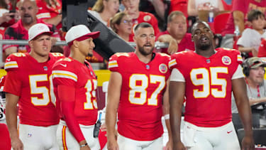 Die vier Chiefs-Spieler George Karlaftis (56), Patrick Mahomes (15), Travis Kelce (87) und Chris Jones (95) stehen an der Seitenlinie in Uniform.
