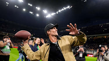 Tom Brady wirft 2026 im Mailänder San Siro den Fans einen Ball zu.