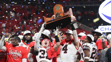 Dec 6, 2025; Atlanta, GA, USA; Georgia Bulldogs running back Cash Jones (32) and Georgia Bulldogs tight end Oscar Delp (4) lift the SEC Championship trophy after the game against the Alabama Crimson Tide during the 2025 SEC Championship game at Mercedes-Benz Stadium. Mandatory Credit: Brett Davis-Imagn Images